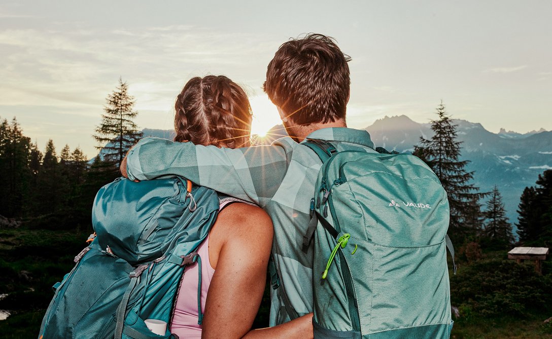 Paar mit Wanderrucksäcken genießt Sonnenuntergang in den Bergen