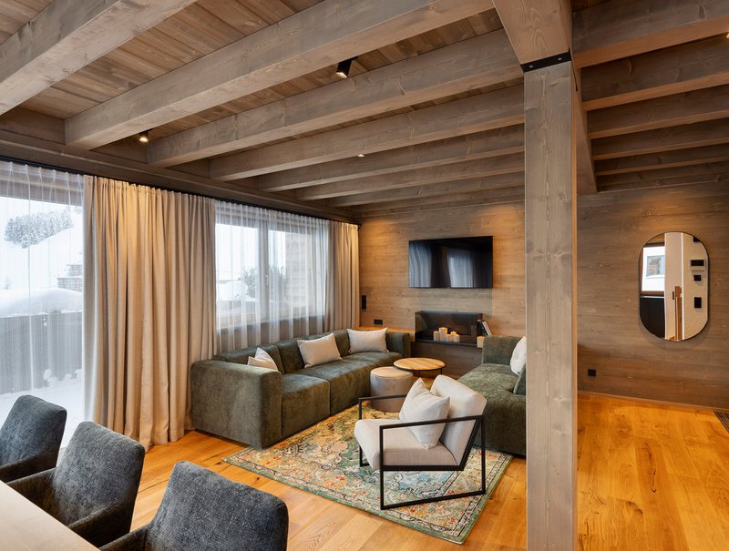 Gemütliches Wohnzimmer eines Chalets mit Holzbalkendecke und modernen Möbeln