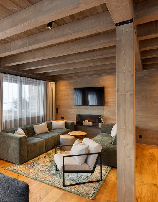 Gemütliches Wohnzimmer eines Chalets mit Holzbalkendecke und modernen Möbeln