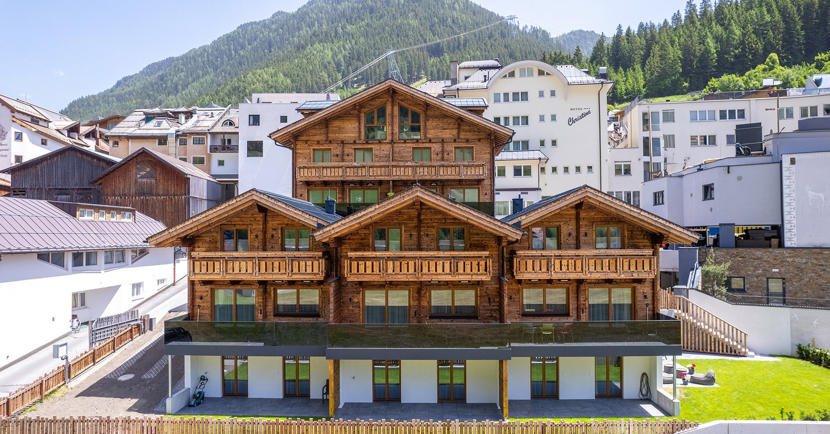 Holzchalet - Luf Lodges inmitten von Ischgl mit Bergkulisse von Alpen im Hintergrund